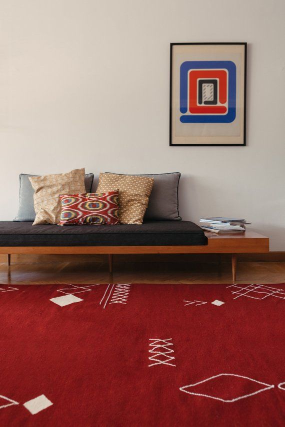 Kilim rug in red color place in a room with bench and cushions on them.